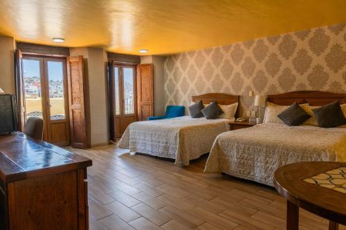 a hotel room with two beds and a flat screen tv at Hotel Casa Santa Lucia in Zacatecas