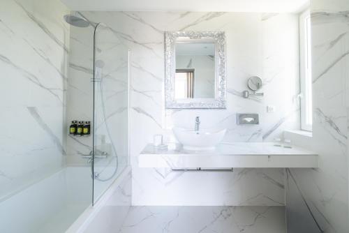 a white bathroom with a sink and a shower at Hôtel La Villa Cap d’Antibes in Juan-les-Pins