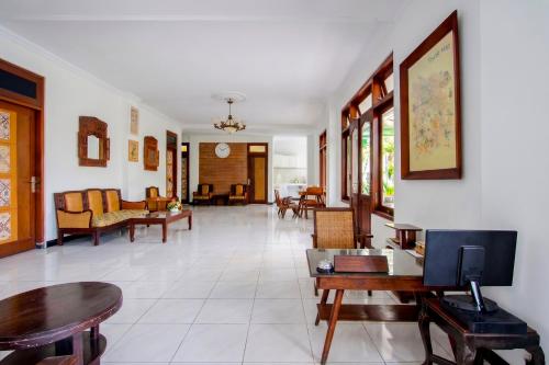 a living room with tables and chairs and a tv at Hotel O near Alun-Alun Kidul formerly Ndalem Mantrijeron Hotel in Yogyakarta