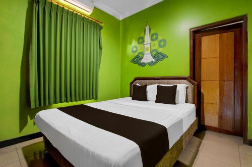 a bedroom with a bed with green walls at Hotel O near Alun-Alun Kidul formerly Ndalem Mantrijeron Hotel in Yogyakarta