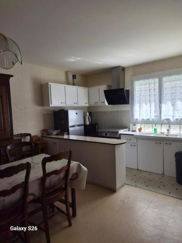 a kitchen with white cabinets and a table and a table and chairs at maison village in Xambes