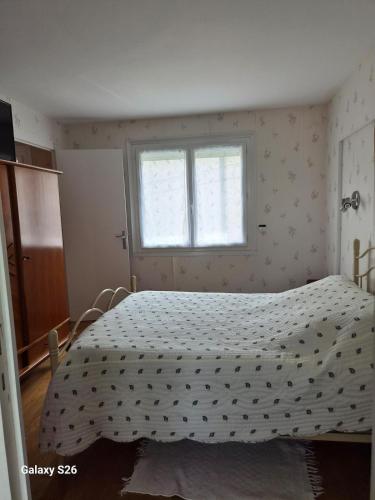 a bedroom with a bed with a white comforter and a window at maison village in Xambes
