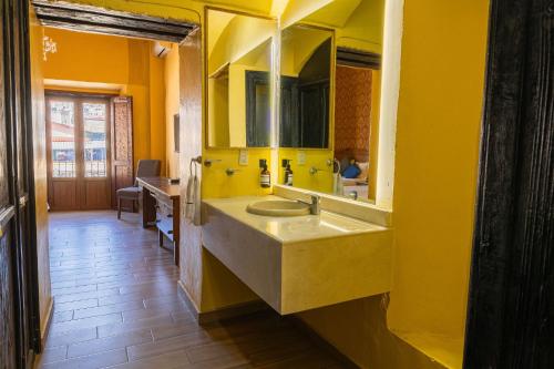 a yellow bathroom with a sink and a mirror at Hotel Casa Santa Lucia in Zacatecas