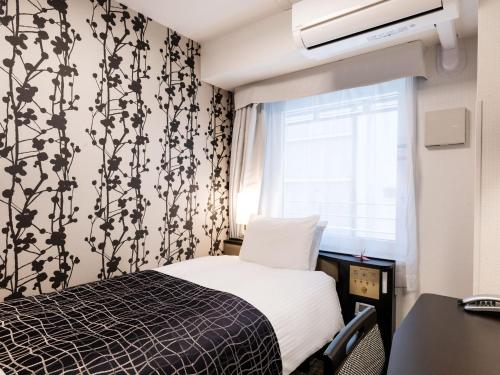a small bedroom with a bed and a window at APA Hotel Kyoto Ekimae Chuoguchi in Kyoto