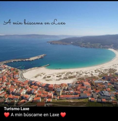 a view of a beach with a town and the ocean at Vivienda Turística Ático in Laxe