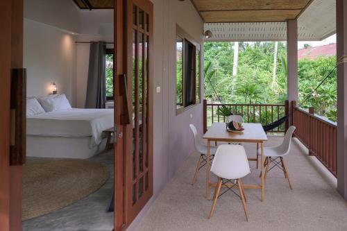 a room with a bed and a table and chairs at Boonya Swiss Home in Chaloklum