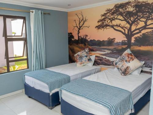 two beds in a room with a painting on the wall at Tlatso lifestyle and Accommodation in Hammanskraal Station