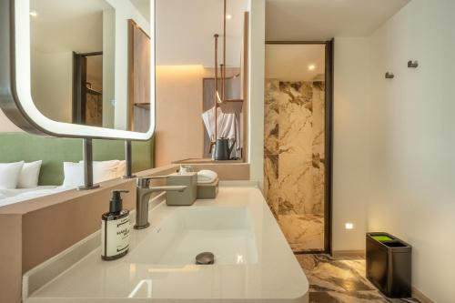 a bathroom with a sink and a mirror at ROYS Hotel Bangkok in Bangkok