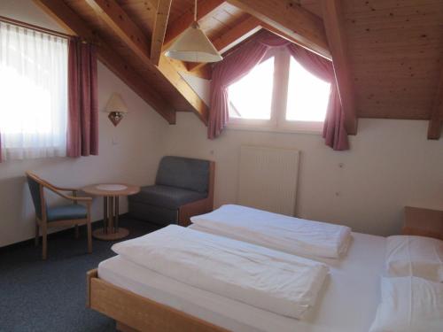 a bedroom with two beds and a chair and a window at Appartements Johann Bachmann in San Candido