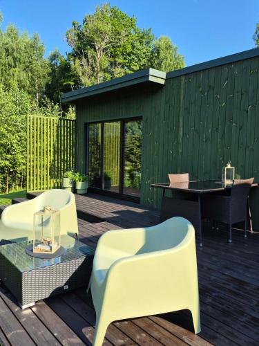 eine Terrasse mit zwei weißen Stühlen und einem Tisch in der Unterkunft SikaSpot Green in Sika