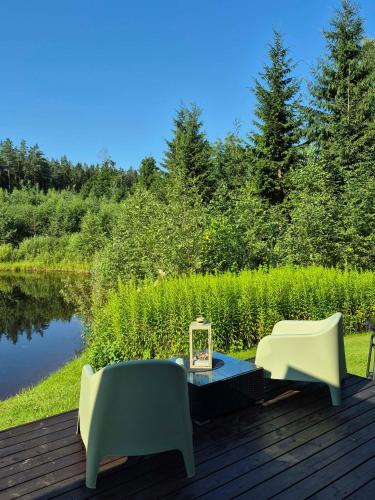 zwei Stühle und ein Tisch auf einer Terrasse neben einem See in der Unterkunft SikaSpot Green in Sika