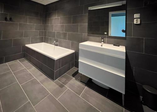 a bathroom with a sink and a bath tub and a mirror at The Mansion in Wijnjewoude