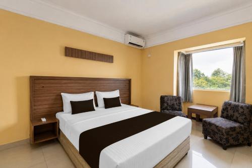 a bedroom with a bed and two chairs and a window at Hotel O near RSUD Arifin Achmad formerly Damon Butik Hotel in Limbangan