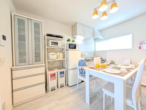 a kitchen with a white table and a table and chairs at Maison New River B-203 in Chiharachō