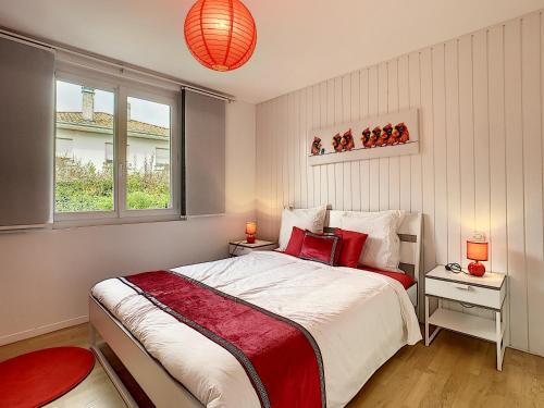 a bedroom with a large bed with red accents at Villa Dedele in Soustons