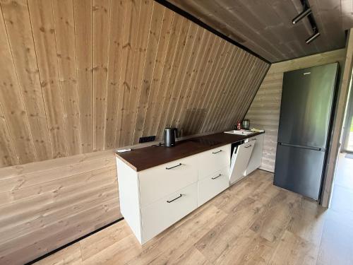 a kitchen with white cabinets and a refrigerator at Frame Village in Žaugėdai