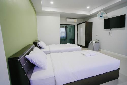 two beds in a hotel room with white sheets at โรงแรมคุณหญิงโฮเตล in Nan