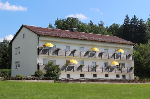 a building with chairs and yellow umbrellas on it at Haus die Gerti - Ilz in Waldkirchen
