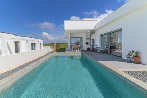 a swimming pool in front of a house at Vila Adelino in Sines