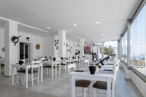 a restaurant with white tables and chairs and windows at Santorini View in Akrotiri