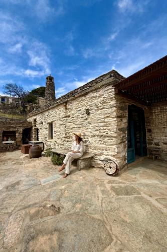 a woman sitting on a bench outside of a building at Nostos Kea in Káto Meriá
