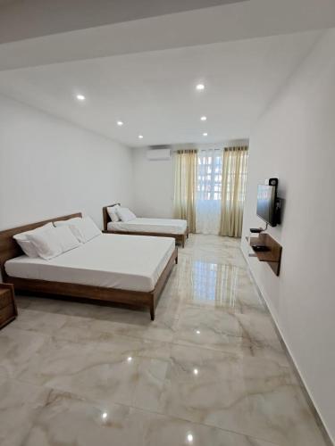 a bedroom with two beds and a flat screen tv at Caterina Suites in Wied l-Arkata