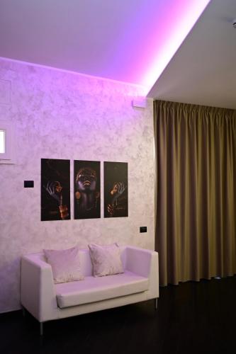 a white couch in a room with paintings on the wall at ASTRUM b&b in Cosenza
