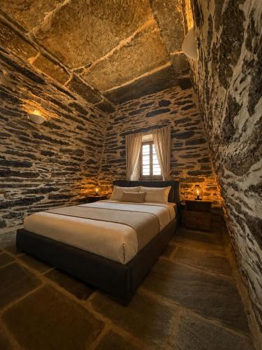 a bedroom with a large bed in a stone wall at Nostos Kea in Káto Meriá