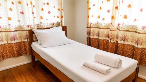 a bed in a room with curtains and towels at Auki Ocean View in Auki