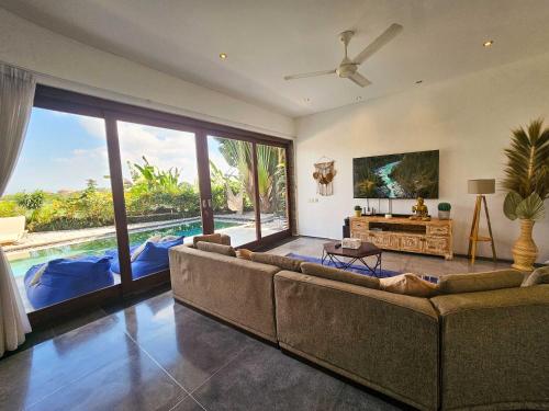a living room with a couch and a large window at Villa Dew Canggu in Kerobokan