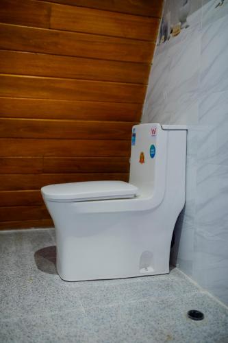 a white toilet in a bathroom with a wooden wall at Area 51 Arugambay in Arugam Bay