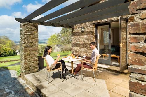 a man and woman sitting at a table on a patio at Trenython Manor Resort in Fowey