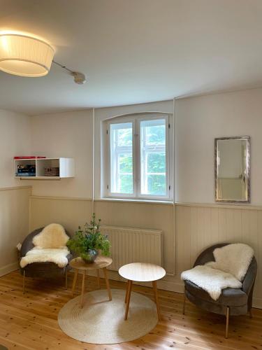 a living room with two chairs and a table and a window at Lundsgaard Gods ferielejlighed in Kerteminde