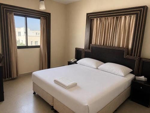 a bedroom with a large bed and a window at Dolphin Hotel in Muscat