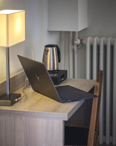 a laptop computer sitting on top of a wooden desk at Hôtel de la Poste Restaurant Benjamin Linard in Pouilly-en-Auxois