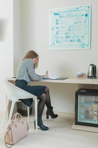 a woman sitting at a desk writing on a paper at Helios Hotel in Monza