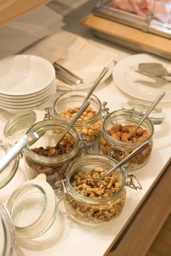 four jars of nuts on a counter with plates and dishes at Helios Hotel in Monza