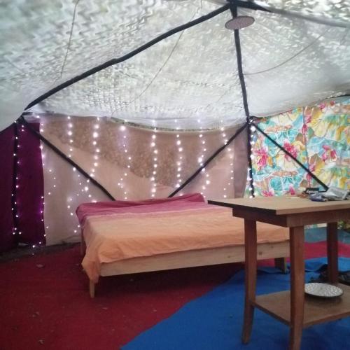 a bed in a tent with a table at La GéoYourte in Saint-Vincent