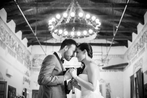 a bride and groom are kissing under a chandelier at Castello di Altomonte in Altomonte