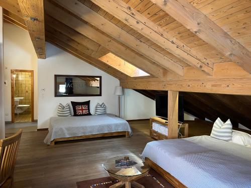 two beds in a room with wooden ceilings at Albana Hotel Silvaplana in Silvaplana