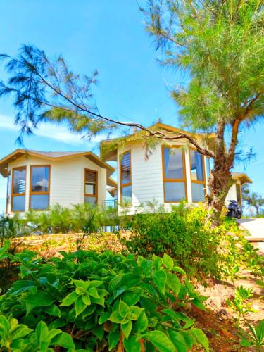 a white house with a tree in front of it at Hon Do Eco Retreat in Mỹ Thanh