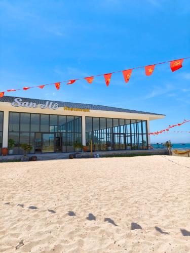 a building on the beach with flags in front of it at Hon Do Eco Retreat in Mỹ Thanh