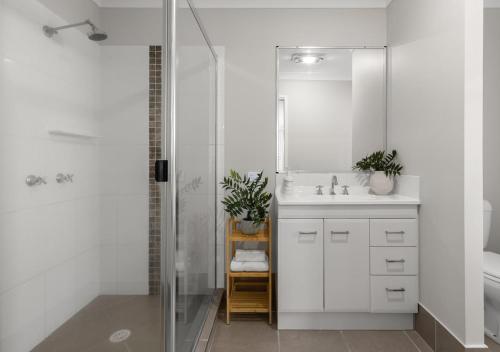 a white bathroom with a shower and a sink at Blue Gum Hideaway Pet friendly Fire Pit in Coolum Beach