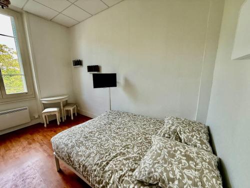 a white bedroom with a bed and a window at Studio plein centre et parking in Châtel-Guyon