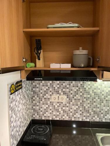 a kitchen with a stove and a counter top at Apartemen Roseville at BSD by Kenkei in Dadap