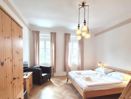 a bedroom with a bed and a chair and a chandelier at Das Sonnengleis in Lutzmannsburg