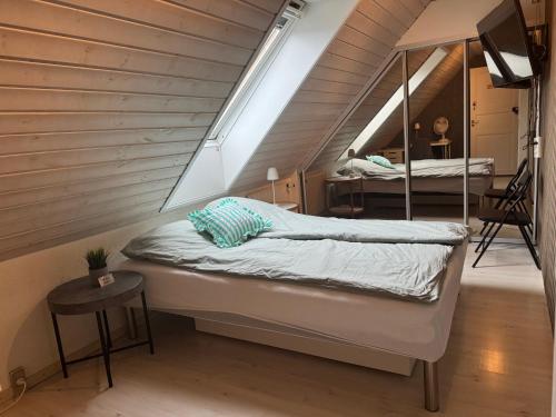a attic bedroom with a bed and a mirror at Villa Malena Guesthouse in Fensmark