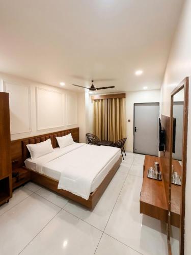 a bedroom with a large white bed and a television at Hotel Vivanta in Bānswāra
