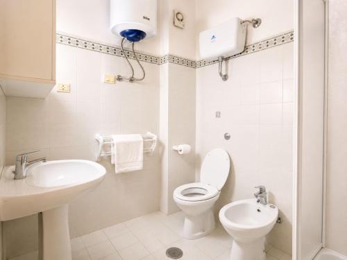 a white bathroom with a toilet and a sink at Cala Rossa 35 Wit Pool - Elba Affitti in Nisporto