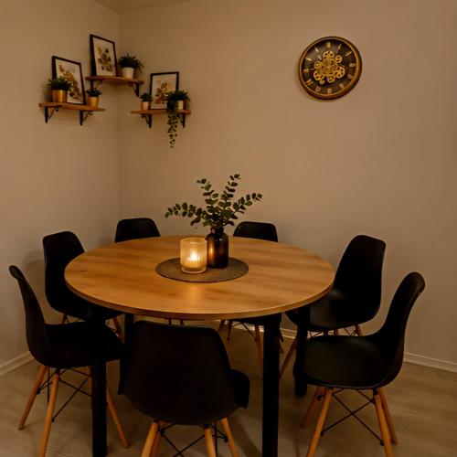 a dining room table with chairs and a clock on the wall at Casa de Flores in Knjazevac.